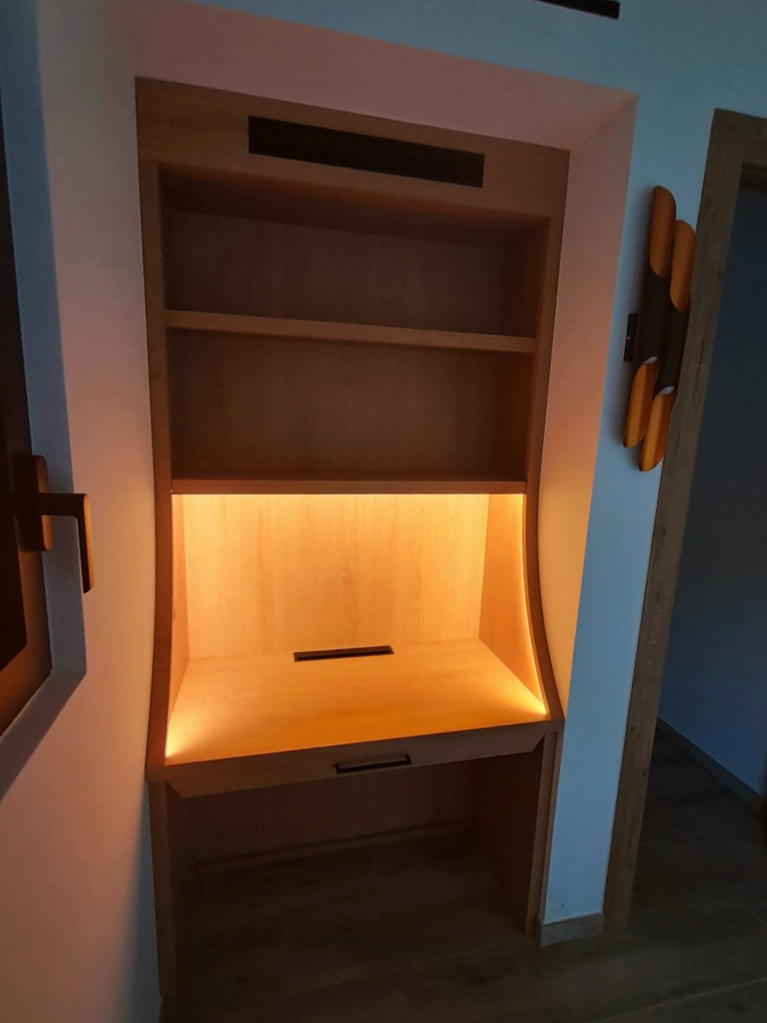 Un bureau en bois massif, épuré et fonctionnel, avec un large plateau, des rangements intégrés et un éclairage LED.