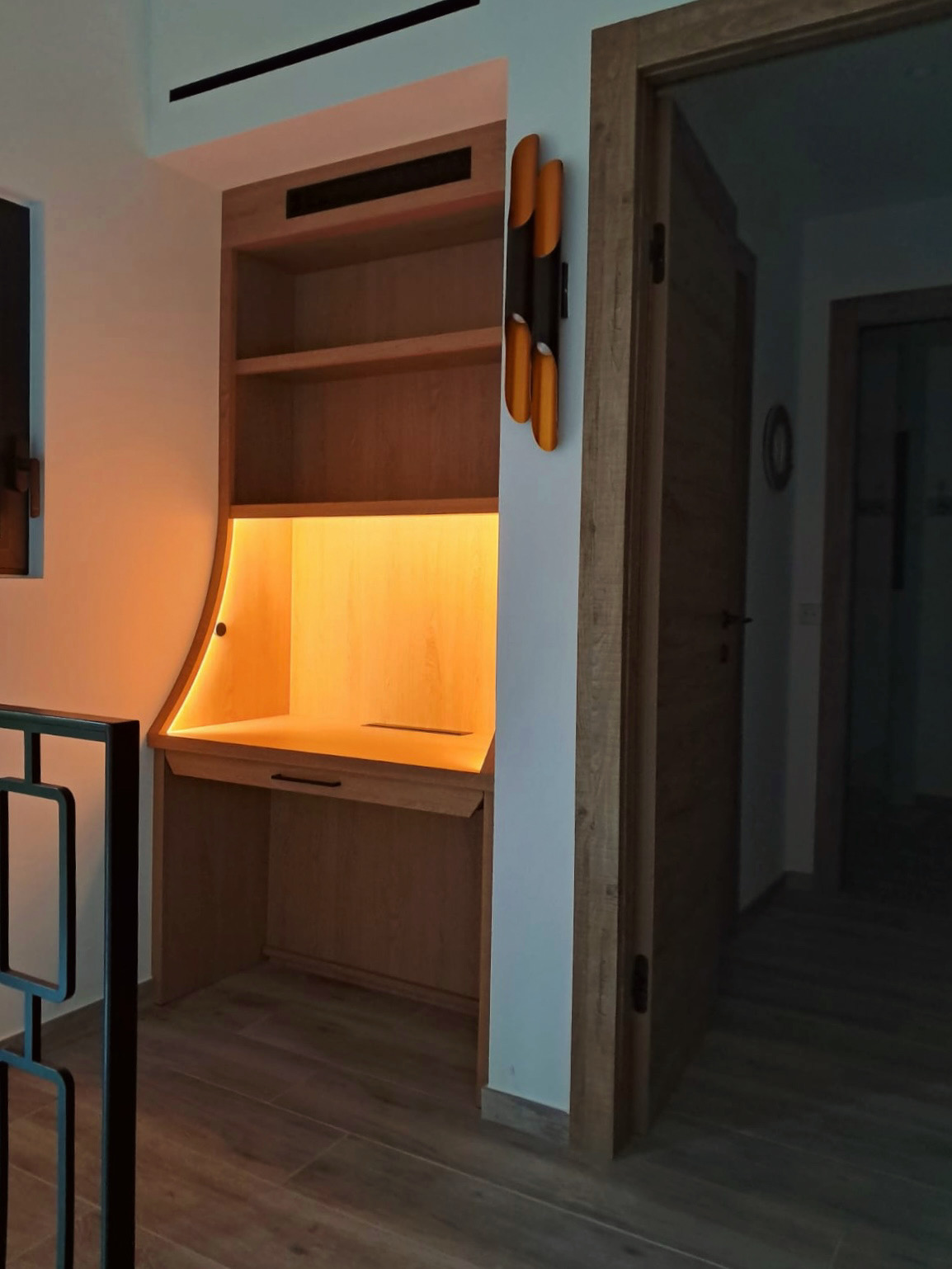 Un bureau encastré en bois, conçu sur mesure, offrant un espace de travail optimisé avec des rangements intégrés et un éclairage LED élégant.