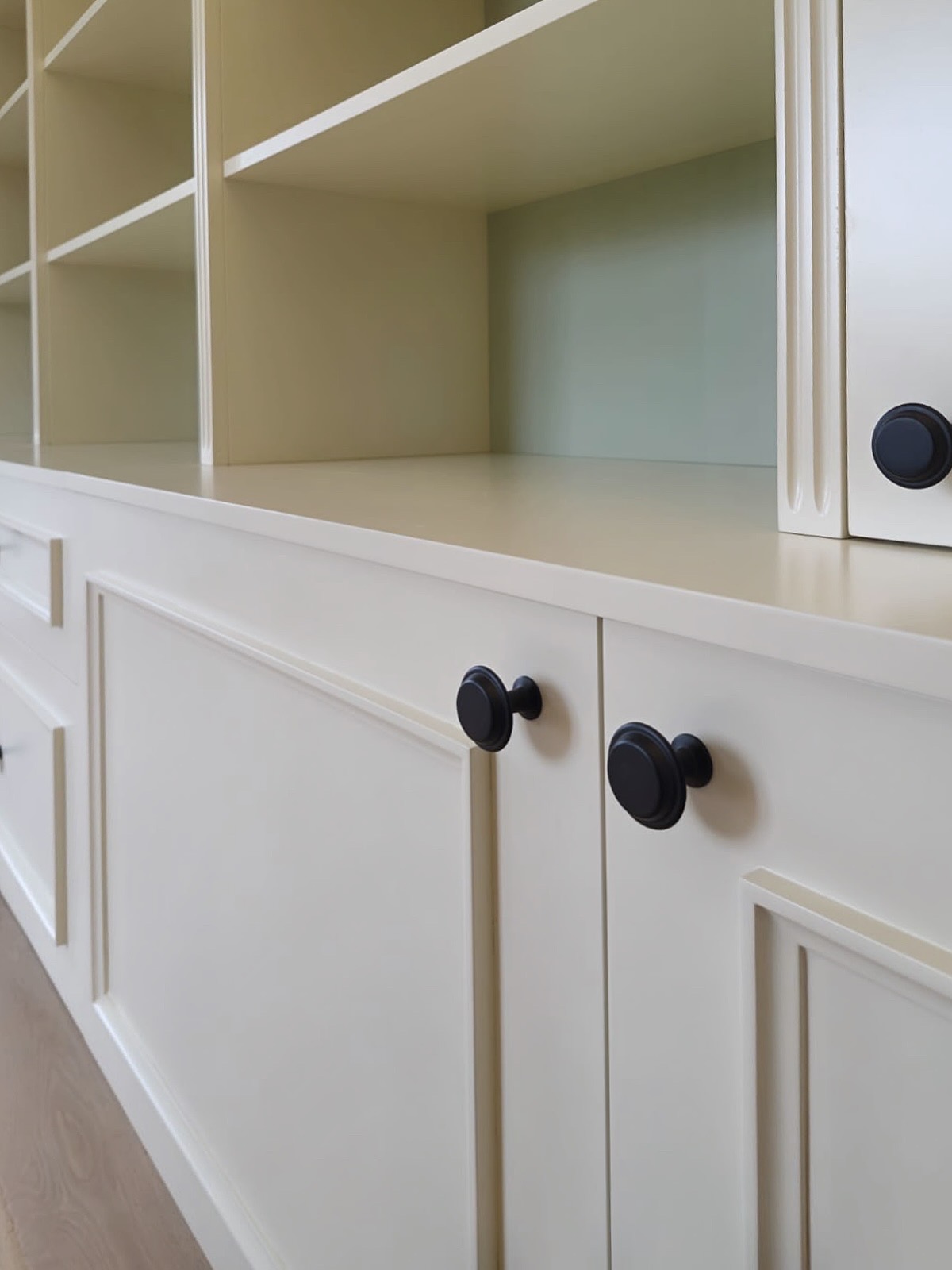 Bibliothèque sur mesure à Mougins, portes laquées crème et fond vert, agencement pensé pour un intérieur harmonieux et lumineux